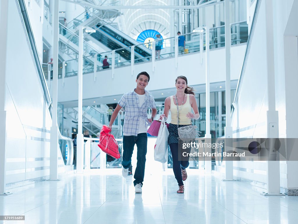 Sorridente Casal corrida com sacos de compras no centro comercial de transporte