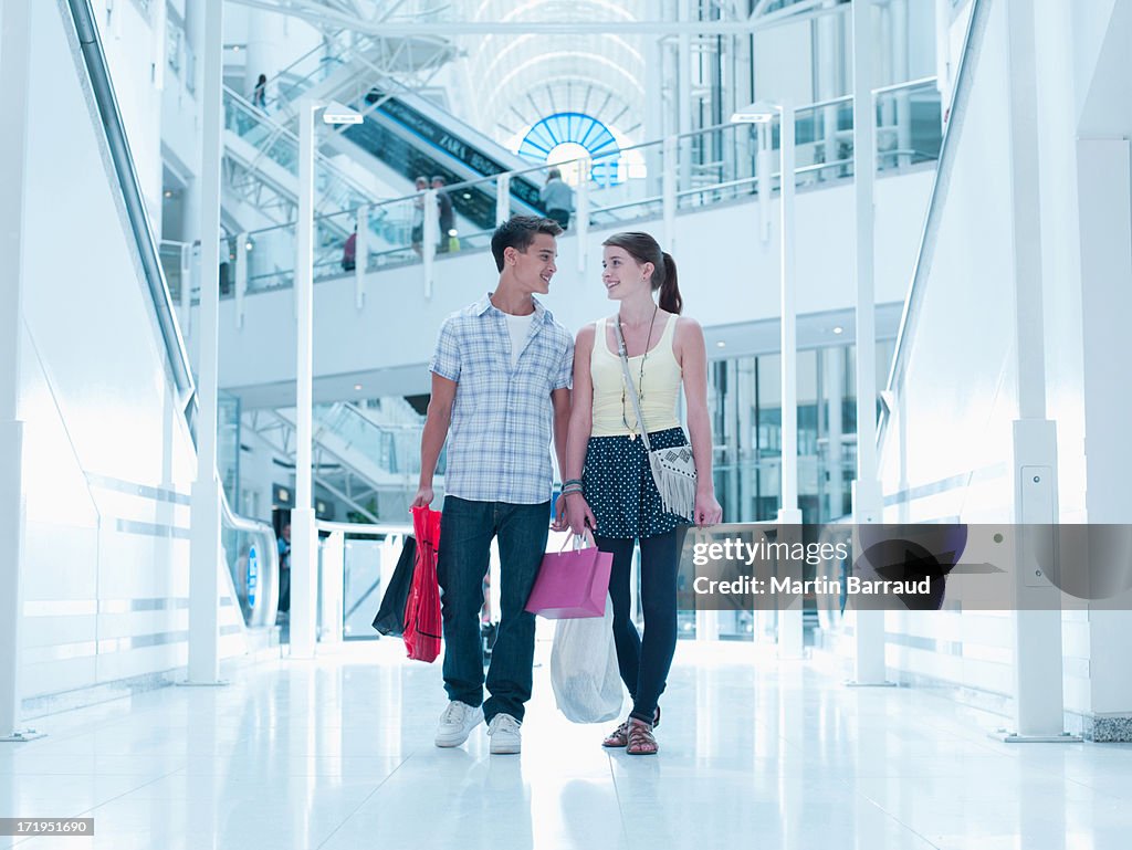 Smiling couple carrying shopping bags in mall