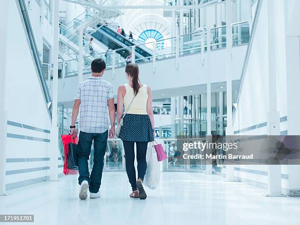 couple carrying shopping bags in mall - couple shopping in shopping mall stock pictures, royalty-free photos & images