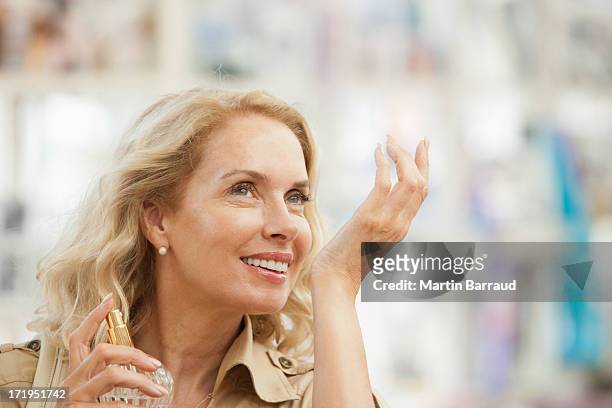 smiling woman testing perfume in store - choosing perfume stock pictures, royalty-free photos & images