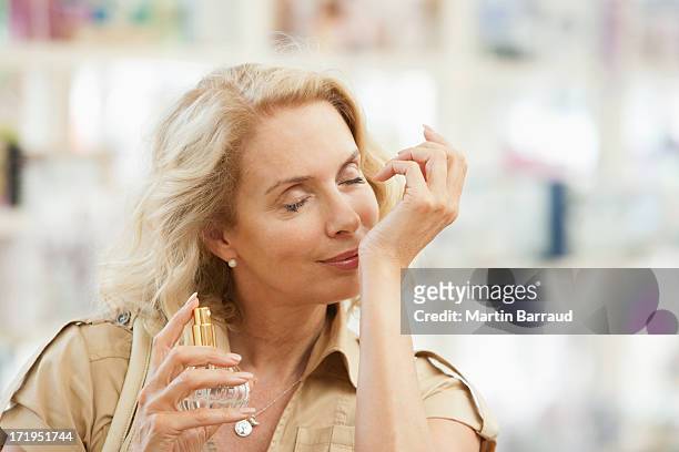 donna sorridente test profumo in negozio - parfum foto e immagini stock