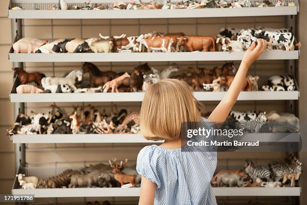 fille à atteindre la vache en plastique en magasin de jouets - toy animal stock photos et images de collection