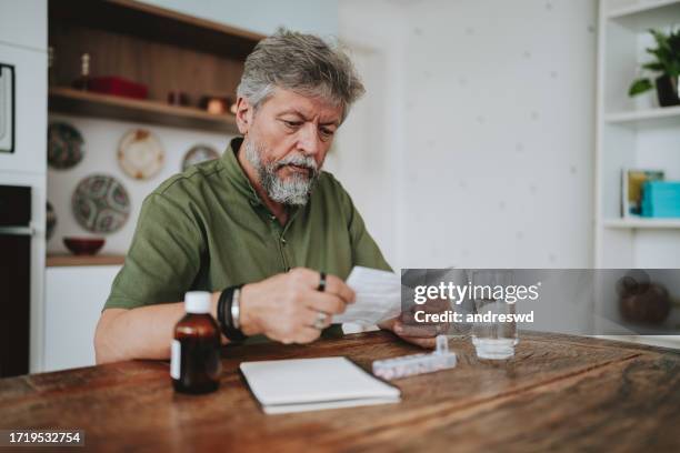 senior man checking medical prescription at home - taking pills stock pictures, royalty-free photos & images