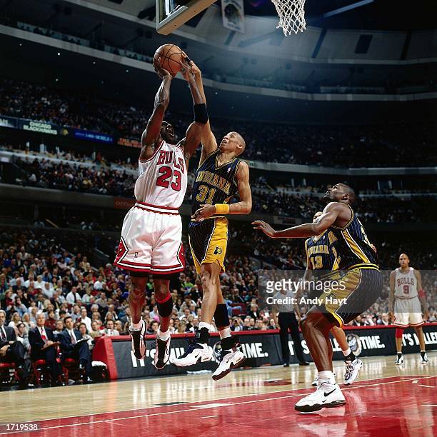 Reggie Miller of the Indiana Pacers goes up to block a shot against Michael Jordan of the Chicago Bulls during the NBA game at the United Center in...