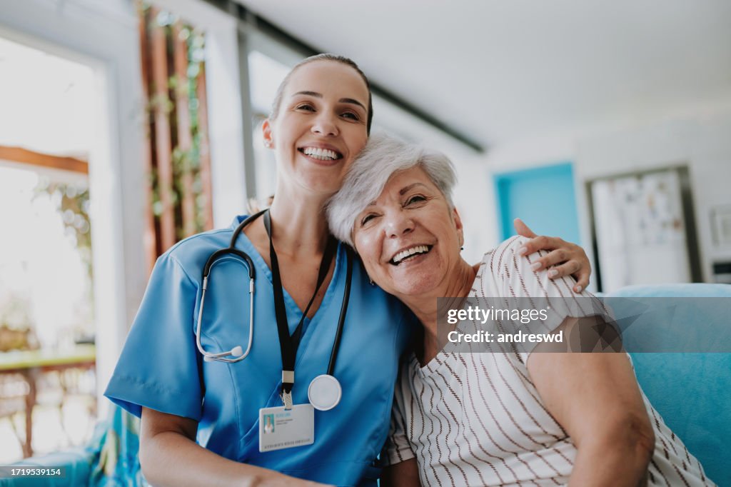 Profesional de la salud de atención domiciliaria abrazando a un paciente mayor