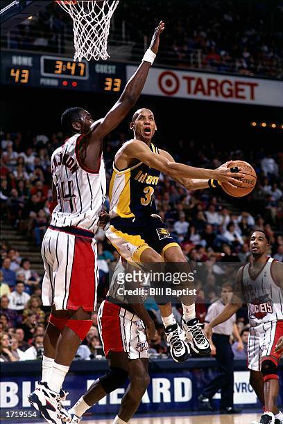 Reggie Miller of the Indiana Pacers drives to the basket against Hakeem Olajuwon of the Houston Rockets during the NBA game at the Summit in 1996 in...