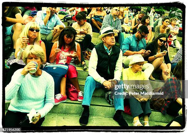 Spectators wait to watch a match on a giant TV screen at The Wimbledon Lawn Tennis Championships on June 26, 2013 in London, England.