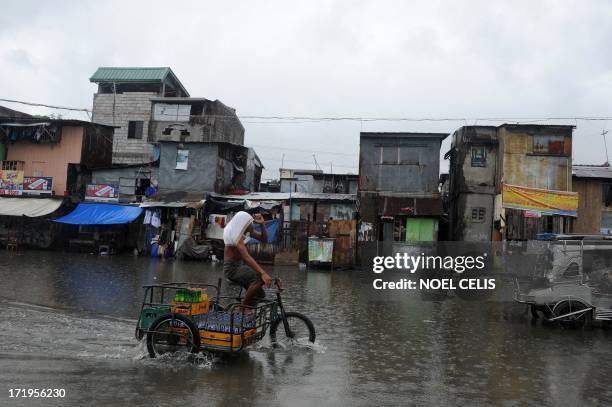 Man on his bike wades through a flooded street in Manila on June 30, 2013. Tropical storm Rumbia lashed Manila and nearby areas with 65-75 kph winds...