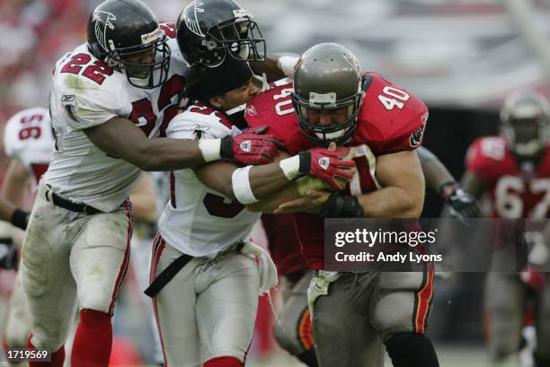 Mike Alstott of the Tampa Bay Buccaneers runs with the ball as Gerald McBurrows of the Atlanta Falcons and Ray Buchanan try to strip the ball from...