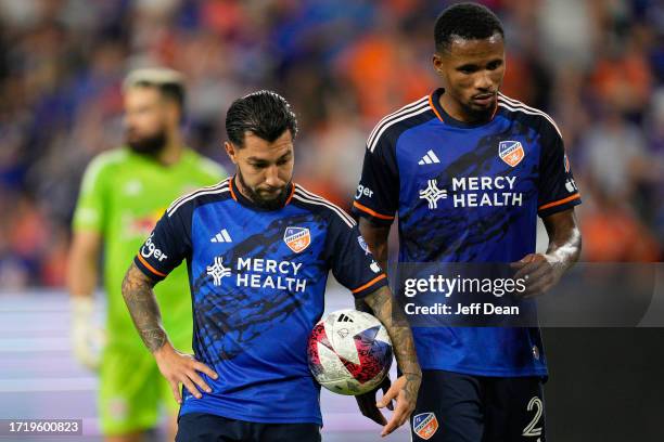 Luciano Acosta stands with Alvas Powell of FC Cincinnati prior to taking a penalty kick during the second half of an MLS soccer match against the New...