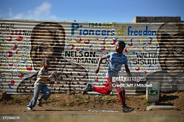 Children run past a mural of former South African president Nelson Mandela and other freedom fighters in the Orlando District of Soweto Township on...