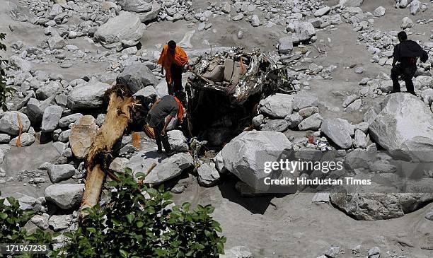 People looks at a wreckage of car beside the bank of river Alaknanda at Govind Ghat on June 30 2013 in Uttarakhand, India.