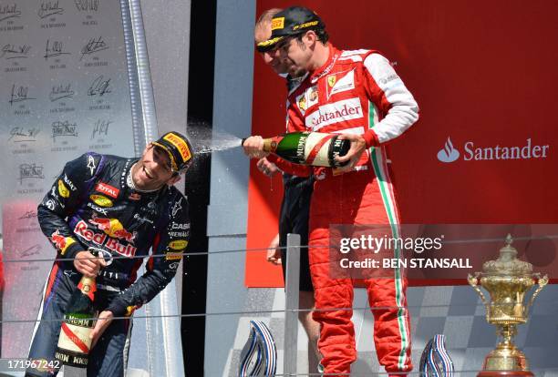 Red Bull Racing's Australian driver Mark Webber and Ferrari's Spanish driver Fernando Alonso spray champagne on the podium at the Silverstone circuit...