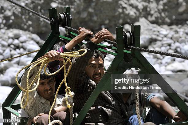 Local people pulling the ropeway with their naked hands to cross the river Alaknanda as the bridge connecting Govind Ghat with the road to Hemkund...