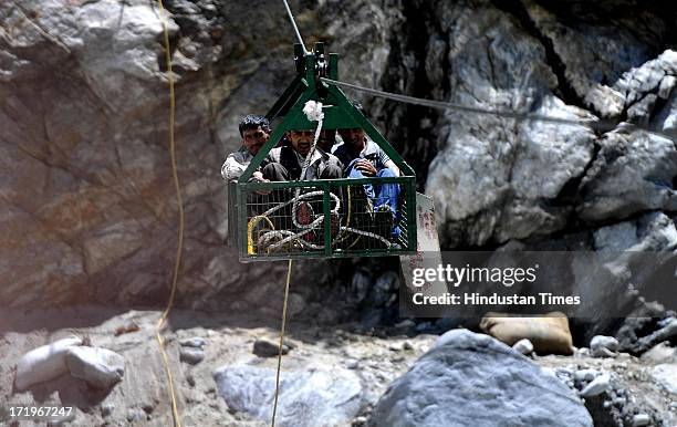 Local people crossing the river Alaknanda in a rope way as the bridge connecting Govind Ghat with the road to Hemkund Sahib Gurudwara is washed away...