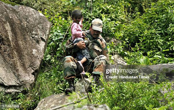 An Army personnel helping a 4yr Khanak Saxena to cross a rocky stretch at Govind Ghat on June 30 2013 in Uttarakhand, India. People who are stranded...