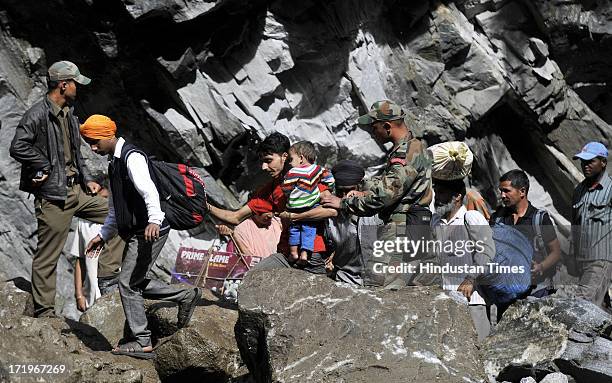 An Army personnel helping people to cross a rocky stretch at Govind Ghat on June 30 2013 in Uttarakhand, India. People who are stranded at Badrinath...