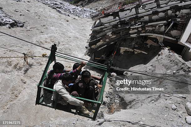 Local people crossing the river Alaknanda in a rope way as the bridge connecting Govind Ghat with the road to Hemkund Sahib Gurudwara is washed away...