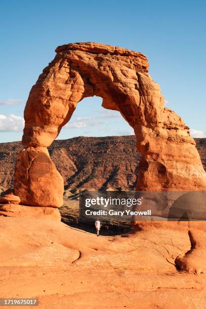 woman standing under and looking up to delicate arch - grand canyon rock formation stock pictures, royalty-free photos & images