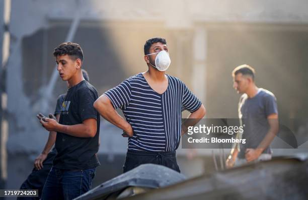 Palestinian citizens search the rubble of a damaged residential building following an airstrike by Israeli warplanes in the Al-Shati refugee camp,...