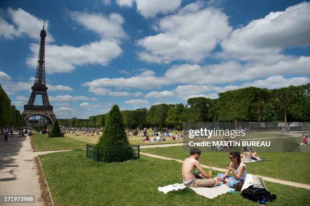 People enjoy the sunny weather in the Champ-de-Mars garden in front of the Eiffel Tower, on June 30, 2013 in Paris. AFP PHOTO MARTIN BUREAU