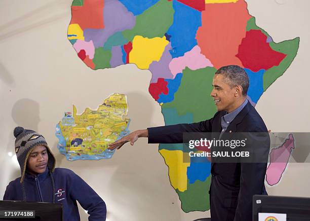 President Barack Obama pretends to drop a microphone alongside Aviwe Mtongana after Mtongana performed a rap during a tour of the Desmond Tutu HIV...