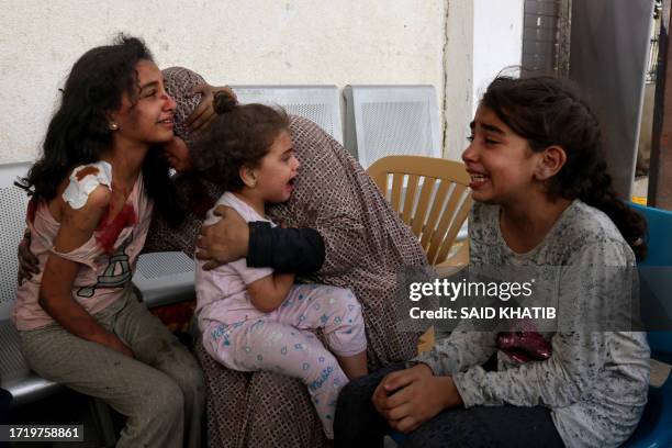 Graphic content / A woman comforts injured Palestinian girls waiting at the hospital to be checked, as battles between Israel and the Hamas movement...