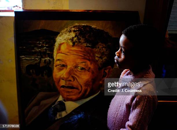Child stands in front of a painting of Former South African President Nelson Mandela at the "Mandela House" museum in the Orlando West section of...