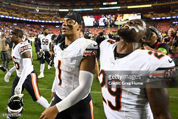 Justin Fields and Tyrique Stevenson of the Chicago Bears react as they leave the field after defeating the Washington Commanders 40-20 at FedExField...