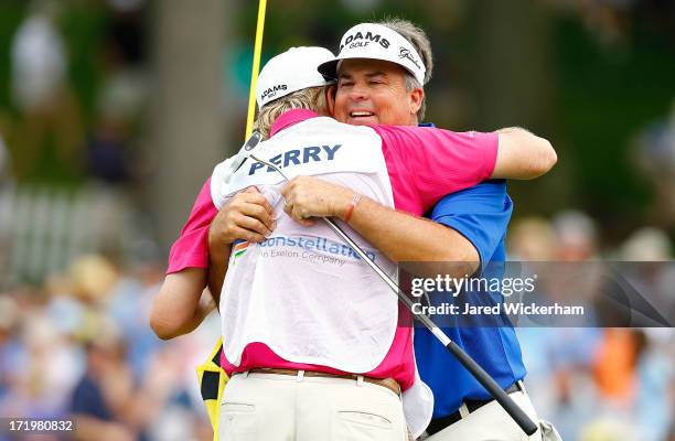 Kenny Perry celebrates with his caddy on the 18th green in the final round after winning the 2013 Constellation Senior Players Championship at Fox...