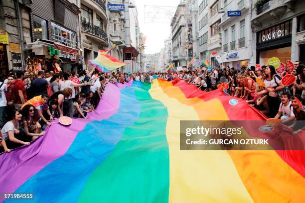 People hold a giant rainbow flag during a gay parade on Istiklal Street, the main shopping corridor on June 30, 2013 in Istanbul during the fourth...