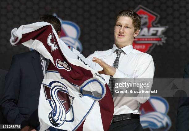 Nathan Mackinnon puts on his jersey after being selected number one overall in the first round by the Colorado Avalanche during the 2013 NHL Draft at...
