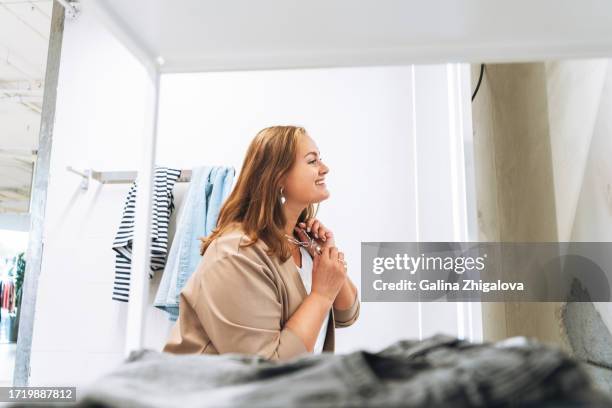 young beautiful woman plus size chooses jewelry and clothes in the fitting room of store - fitting room stock pictures, royalty-free photos & images
