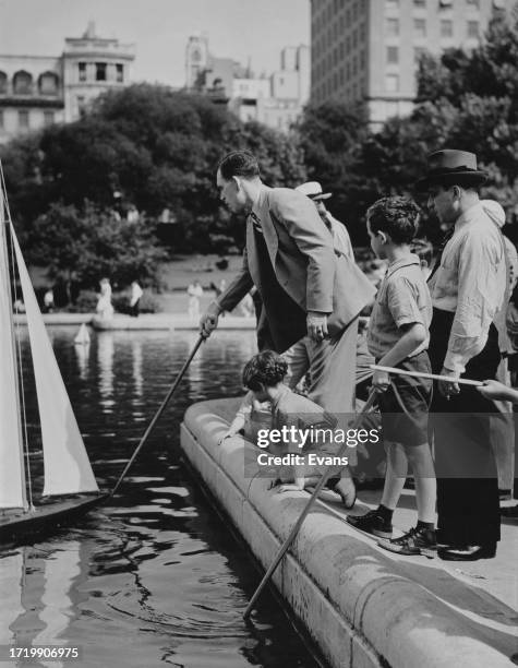 Men and children sailing model boats on Conservatory Water in Central Park, Upper Manhattan, New York City, New York, circa 1935. Central Park is...