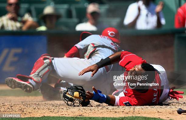 Engel Beltre of the Texas Rangers reacts in pain after a collision at home plate to score against catcher Devin Mesoraco of the Cincinnati Reds in...