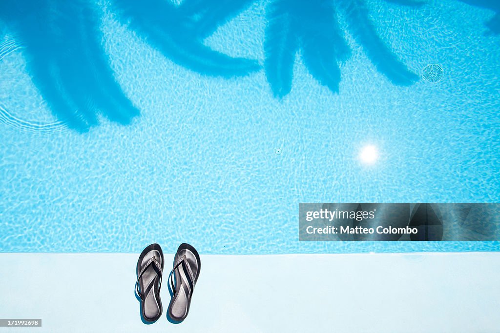 Pair of woman flip flops close to a swimming pool