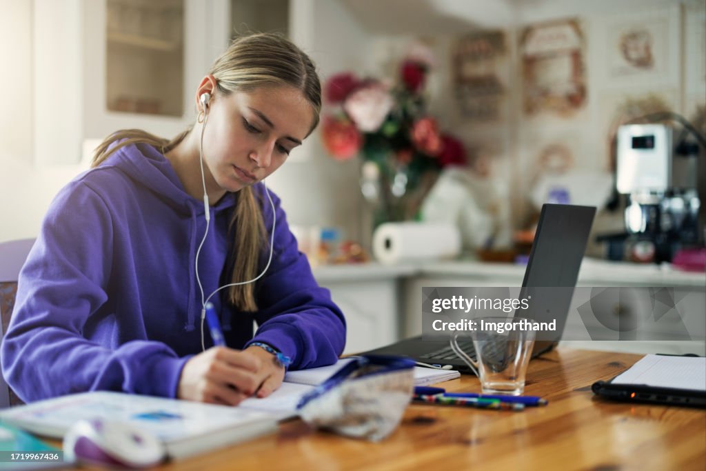 Teenage girl using laptop to do homework at home