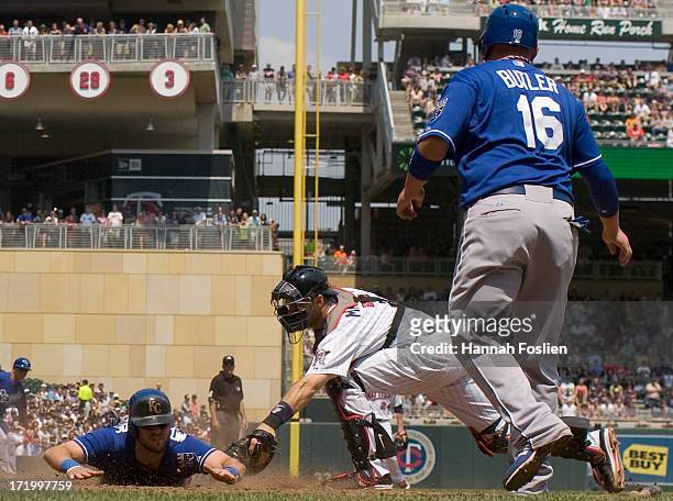 Mike Moustakas of the Kansas City Royals is safe as Joe Mauer of the Minnesota Twins defends home plate and Billy Butler of the Kansas City Royals...
