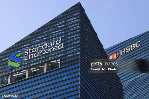 Signage of Standard Chartered Plc and HSBC Holding Plc sit atop of buildings at the Marina Bay financial district on October 12, 2023 in Singapore.