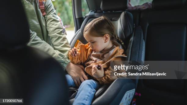 mother buckling up on child in car safety seat - baby car seat stock pictures, royalty-free photos & images