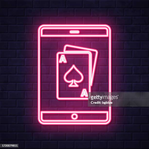 tablet pc with playing card. glowing neon icon on brick wall background - blackjack stock illustrations