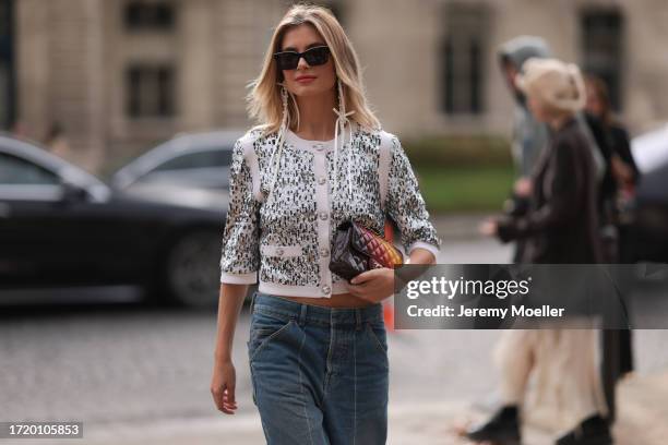 Xenia Adonts is seen outside Chanel show wearing black Chanel sunnies, Chanel pearl earrings, Chanel sequin crystal shiny cardigan, Chanel wide leg...