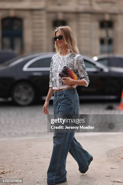 Xenia Adonts is seen outside Chanel show wearing black Chanel sunnies, Chanel pearl earrings, Chanel sequin crystal shiny cardigan, Chanel wide leg...