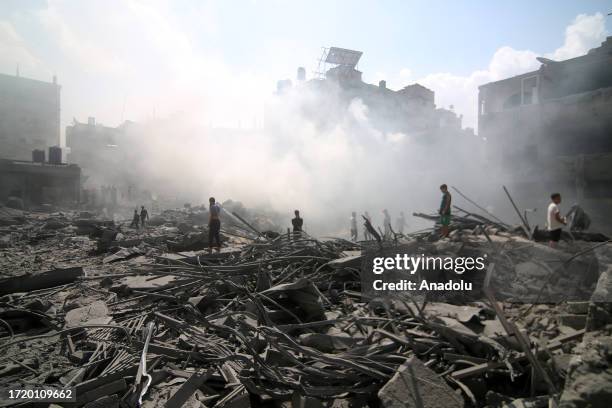 Smoke rises over rubbles of destroyed buildings as civil defense teams conduct an search and rescue operation while Israeli airstrikes continue on...