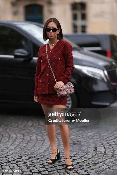 Aimee Song is seen outside Chanel show wearing black Chanel sunnies, golden earrings, a burgundy colored Chanel set consisting of jacket and short...