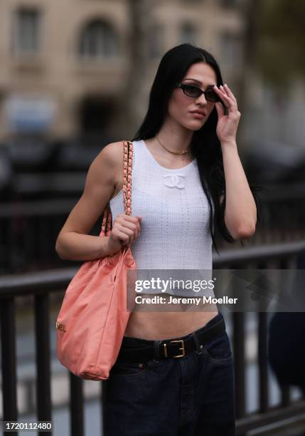 Amelia Gray is seen outside Chanel show wearing black Chanel sunnies, white Chanel tweed tank top and a peach colored Chanel 22 tote leather bag and...