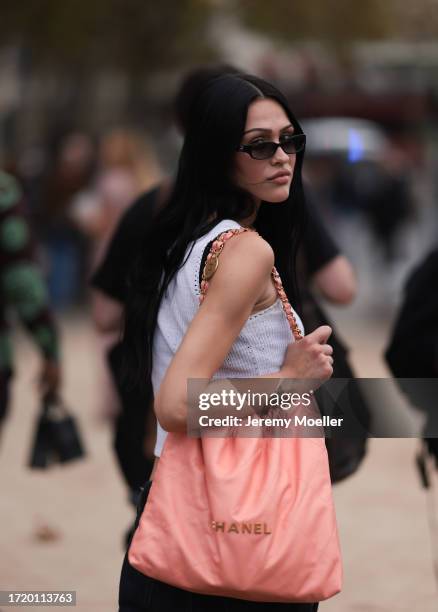 Amelia Gray is seen outside Chanel show wearing black Chanel sunnies, white Chanel tweed tank top and a peach colored Chanel 22 tote leather bag and...