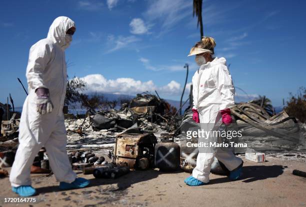 Displaced residents William Anthony and Lori Brodeur walk while searching for personal items in the rubble of the wildfire destroyed home where they...