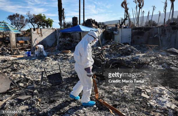 Displaced residents Caroline Anthony and Lori Brodeur search for personal items in the rubble of the wildfire destroyed home where they lived on...