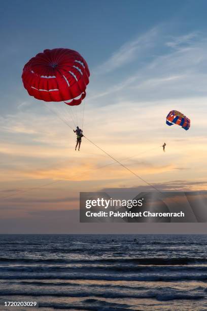 parachute, para sailing over patong beach, phuket thailand during sunset under brilliant storm clouds. - parasailing stock pictures, royalty-free photos & images